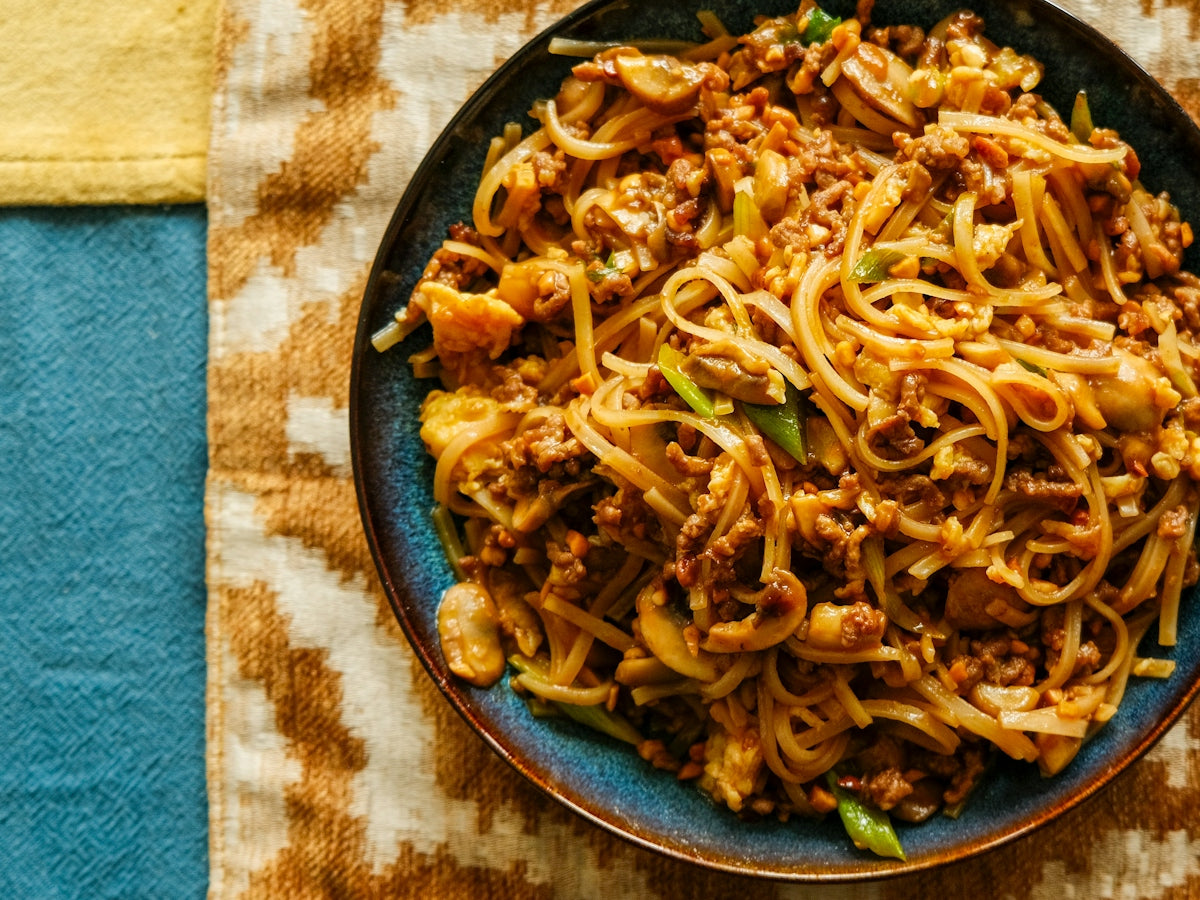 A plate of noodles and meat on a table